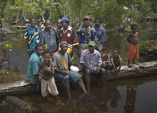 Community members of Lopahan show off mangrove shoots from their mangrove nursery that they are using to resist the encroaching lagoon. Photo: USAID CTSP / Tory Read