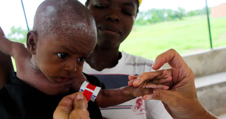 An infant is being measured by health workers. Photo credit: Hayley Droppert, Courtesy of Photoshare 