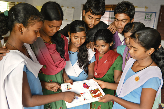 Adolescents gathered around looking at a document