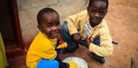 Two young Zambian boys eat orange maize. Photo credit: Chando Mapoma, USAID