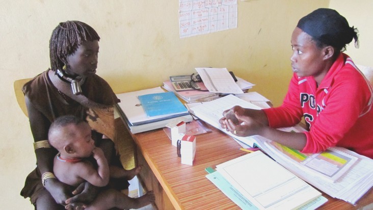 Tarikua Lulayehu, right, a health extension worker at the Aera Keysa health post in the Hamer woreda in Ethiopia, assesses and treats 8-month-old Bora Shewki for pneumonia.