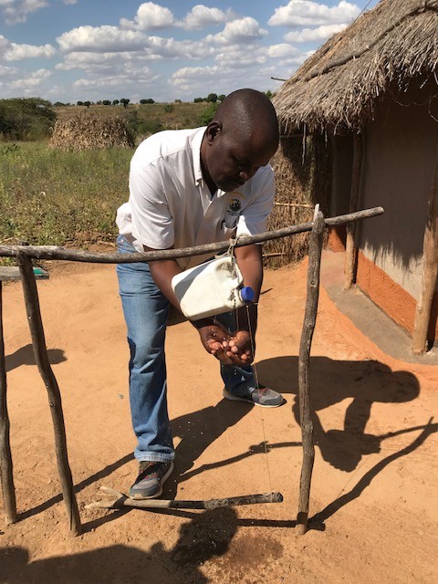 A member of USAID staff washes his hands using a new hands-free hand-washing station.