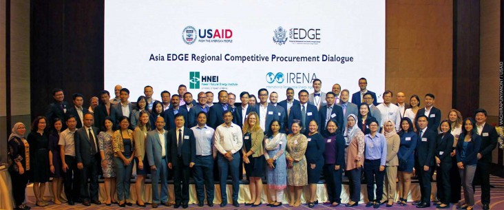 Attendees of the event pose for a group picture in the main hall in front of the event banner