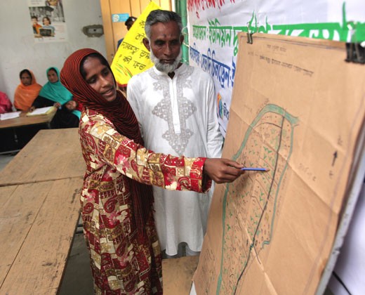 A USAID trainer holds a meeting with community stakeholders to discuss a map of risks and resources.