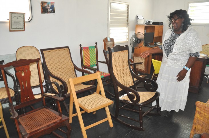 Claudette Thompson shows off the finished chairs that were caned by her team members.