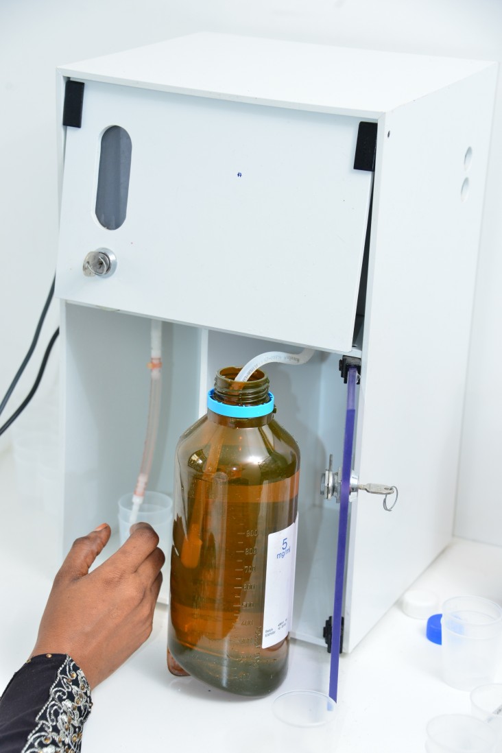 A medical officer dispenses methadone into a cup.