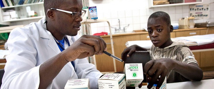 Researcher showing young boy HIV treatment drugs