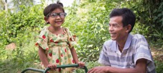 A man smiles with a child wearing glasses