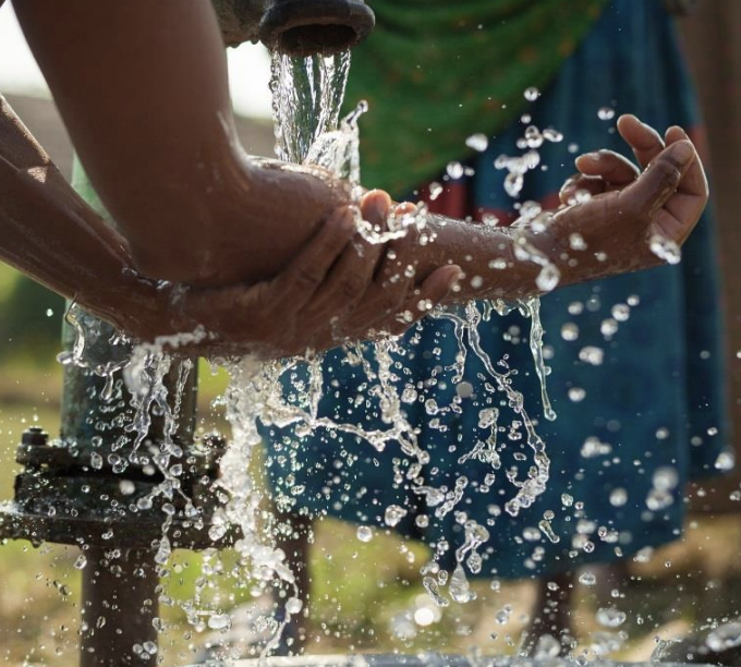 Washing hands at a water pump.