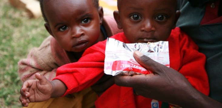 one child drink from nutrition packets while another looks on.