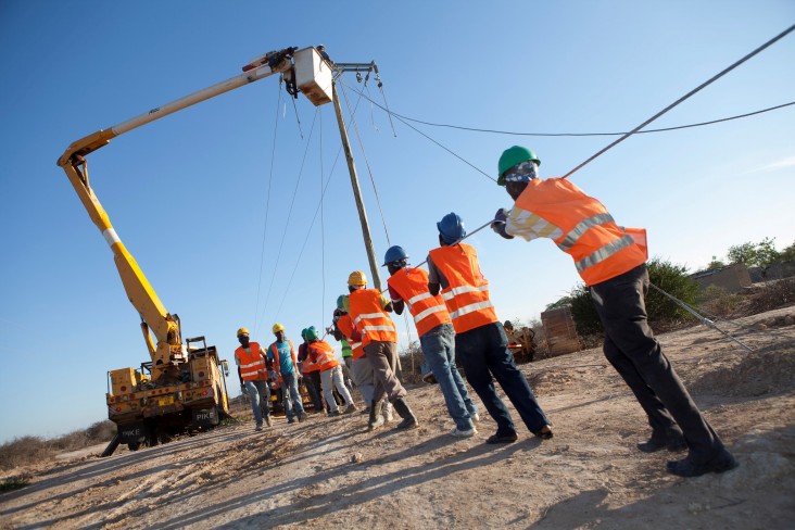 A utility crew from Pike Electric, an American contractor, works to string power lines in rural Dodoma Region, Tanzania. The ini