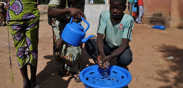 Villagers practice washing their hands using water poured from a pitcher