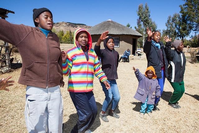 Youth: Key Partners in Controlling the HIV/AIDS Epidemic. A group of young people, waving. Photo credit: USAID/Tash McCarroll