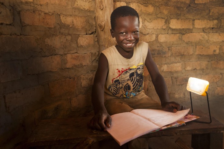 A young boy works on school work using solar light.