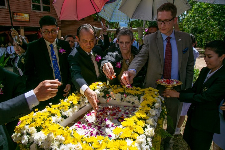 USAID Program Office Director Steven Majors, second from right, lays flowers on the cornerstone for a new hospital in Sangkhlaburi.