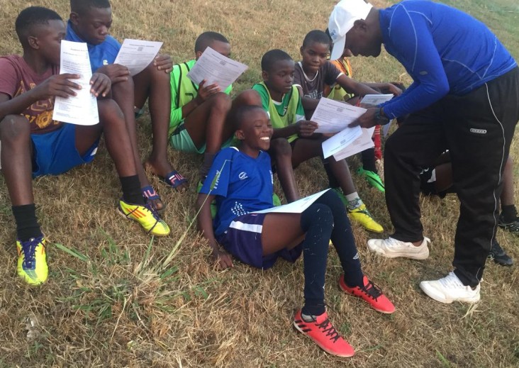 Young men meet with their coach as part of the "Coaching Boys into Men" Program