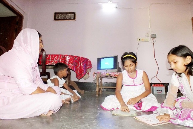 Tania Khatun and her children enjoy watching the solar-powered television. 