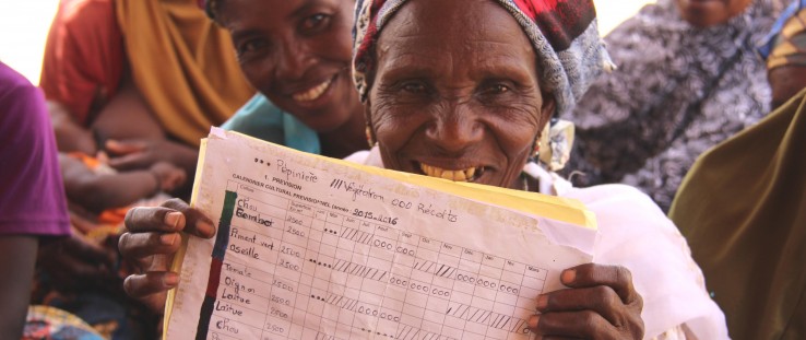 A member of the Albarka women’s group in Iguéfane village holds up a ledger of fruit and vegetable sales from the oasis garden.