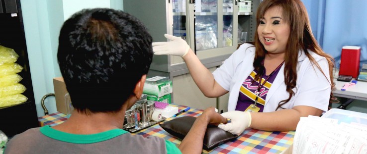 Dusit Meekrua, right, prepares to conduct a finger-prick test at the SWING drop-in center.