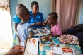 A social worker sits with children around a table.