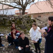 Woman speak in front of a group of women sitting in an outdoor field