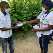 A community relay part of the Xeex Corona team giving a reusable mask to a youth after explaining the barrier measures. SunuElection, USAID