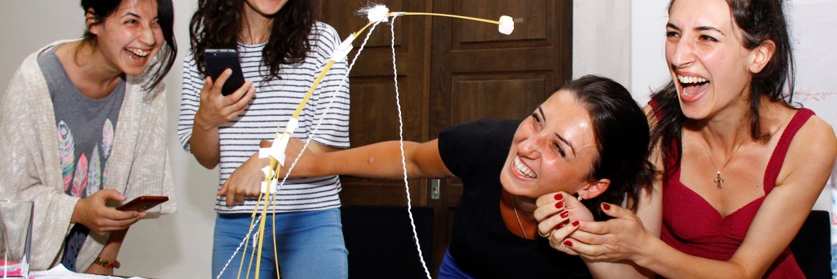 young people laugh as they build a structure from scarp materials